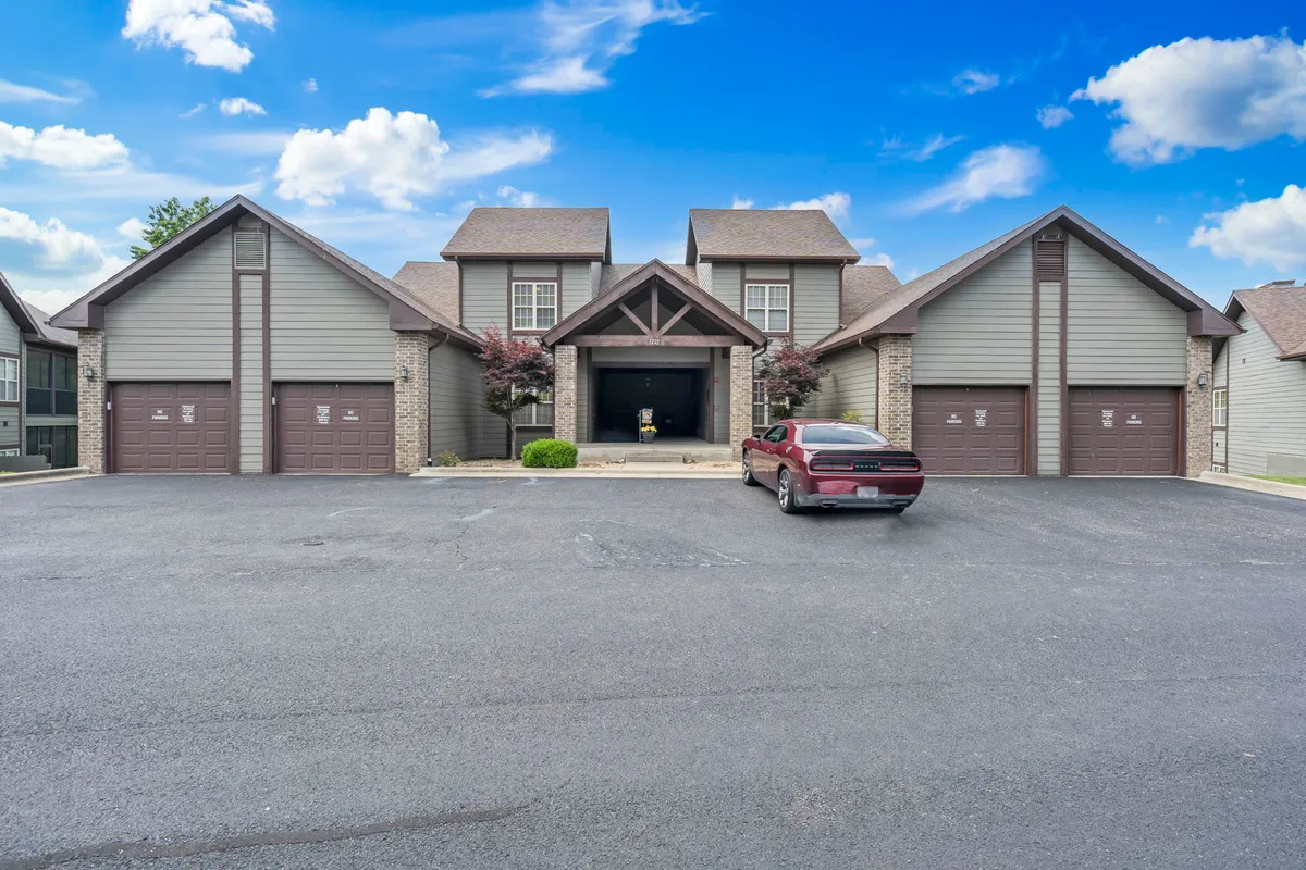 This exterior shot showcases the main entrance of the condo, complete with garage doors and a neatly landscaped area. The welcoming facade suggests ease of access for arrivals and departures, and hints at the inviting community atmosphere.