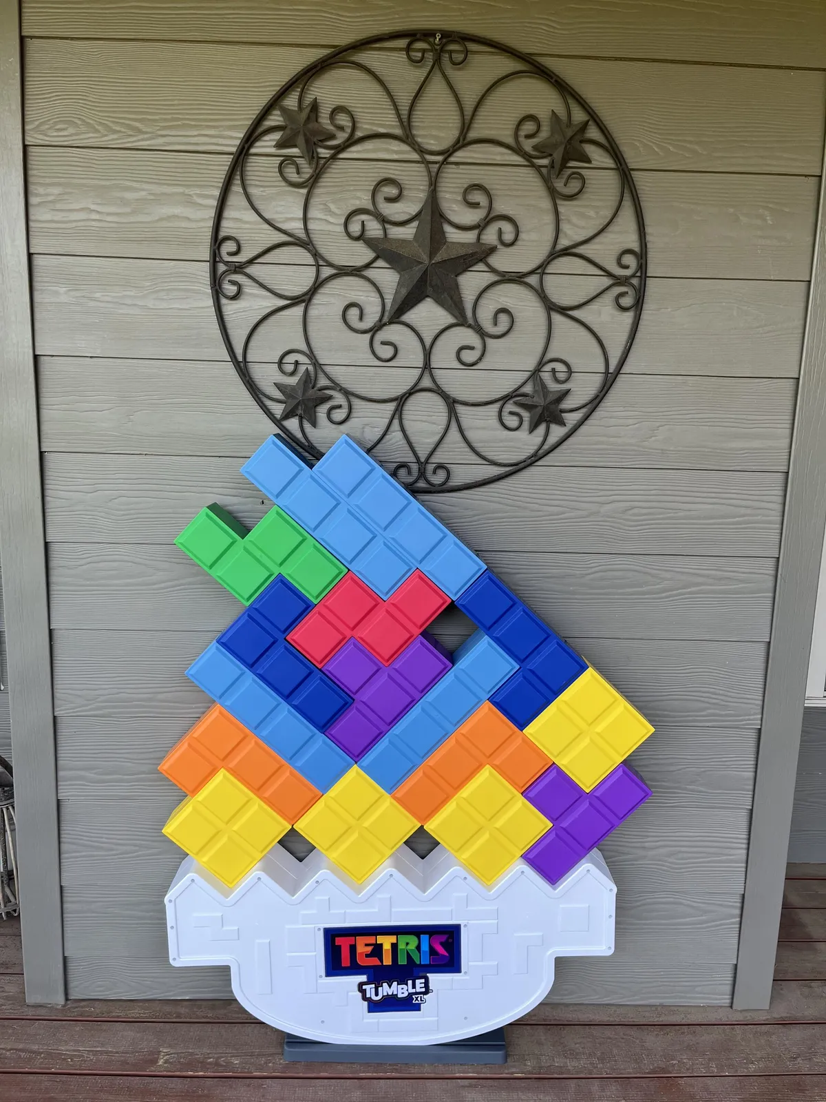 This image captures a playful, Tetris-themed life-size game display set against decorative wall art. The scene radiates joy, with colorful pieces inviting friendly competition and interactive outdoor play for both kids and adults.
