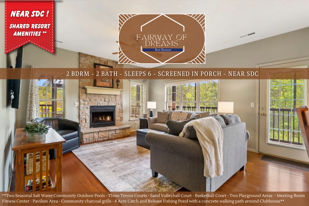 The image showcases a cozy living room interior with plush seating arranged around a warm fireplace. Sunlight pours in through a large window, offering a scenic fairway view. A soft rug anchors the space, inviting guests to relax, play games, or gather for conversations in an inviting, freshly renovated setting.