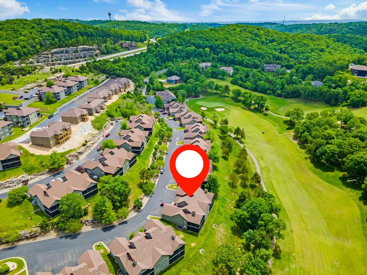 This exterior image showcases a beautifully maintained golf course directly adjacent to neatly arranged condos, all enveloped in lush greenery. The wide view highlights the proximity of accommodations to the fairway, evoking the idea of waking up to or unwinding with scenic golf course views and easy access to golfing activities.